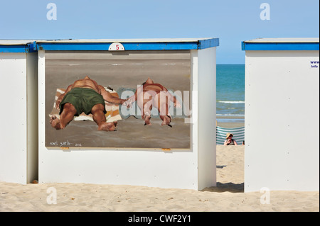 Peinture murale du couple d'obtenir un bronzage tan sur cabine de plage le long de la côte de la mer du Nord à Koksijde / Coxyde, Belgique Banque D'Images
