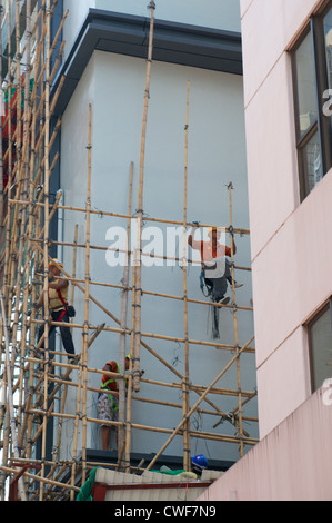 Les travailleurs de la construction les frais généraux le démantèlement de l'échafaudage en bambou à Wan Chai Banque D'Images