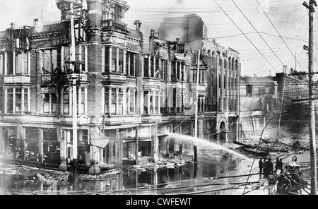 Bloc de bâtiments brûlés à San Francisco après le tremblement de terre de 1906 avec un camion à incendie pulvériser de l'eau sur eux Banque D'Images