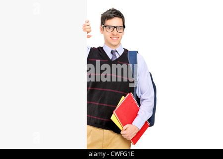 Un male student posing derrière un panneau blanc isolé sur fond blanc Banque D'Images