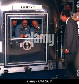 Le président américain Richard Nixon se félicite de l'accueil des astronautes d'Apollo 11 à bord du USS Hornet après son retour de leur vol historique de la lune le 24 juillet 1969 dans l'océan Pacifique. Les astronautes confinés à l'installation de quarantaine mobiles sont (de gauche à droite) Neil A. Armstrong, commandant ; Michael Collins, pilote du module de commande ; et Edwin E. Aldrin Jr., pilote du module lunaire. Banque D'Images