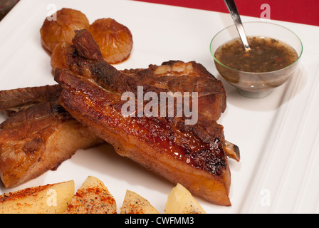 Côtes de porc caramélisées grillé servi avec sauce Chimichurri argentine et garniture Banque D'Images
