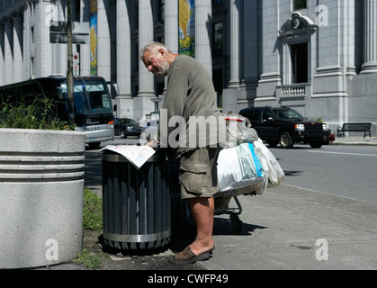 Montréal - un sans-abri lit un journal dans une poubelle Banque D'Images