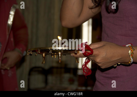 Maintenant la plaque raakhi. Une fille est titulaire de la plaque avec la lampe à huile, se préparer pour attacher le fil sur la main de son frère. Banque D'Images