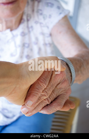 La haute dame en fauteuil roulant et Jeune femme tenant les mains à l'extérieur Banque D'Images