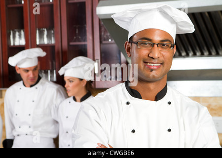 Chef indien professionnel dans la cuisine avec des collègues Banque D'Images