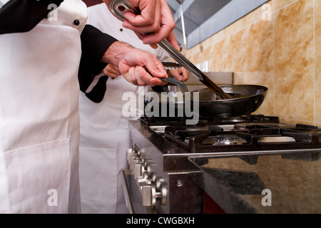 Les chefs professionnels cooking in kitchen Banque D'Images