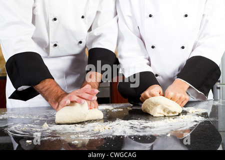 Chef professionnel mains pétrissant la pâte de pain sur le comptoir de la cuisine Banque D'Images