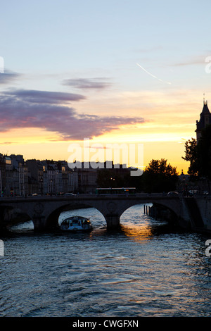Un bateau passe sous un pont sur la rivière de Seine à poussière dans Paris, France Banque D'Images