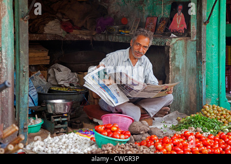 Marchand de journaux de lecture dans un magasin de vente de légumes à Jodhpur, Rajasthan, India Banque D'Images