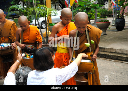 Moines recevant de la nourriture et de vos articles sur le carême bouddhiste Bouddha(jour) sur 12/08/2012 dans le nord-est de la Thaïlande Ubon Ratchathani Banque D'Images