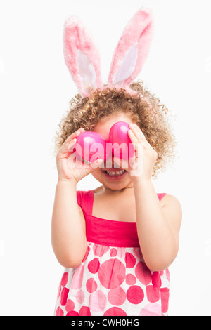 Mixed Race girl à oreilles de lapin et oeufs de Pâques holding Banque D'Images