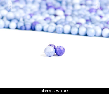 L'une bleue et deux petites perles violet isolé sur fond d'autres perles. Banque D'Images