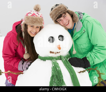 Deux adolescents Building Snowman sur vacances de neige en montagne Banque D'Images