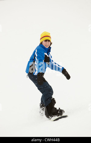 Jeune garçon Snowboard descendre une pente en vacances en montagne Banque D'Images