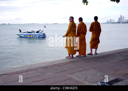 Trois jeunes moines bouddhistes thaïlandais deux face à la mer tandis que l'un regarde leur photo photographe à Pattaya en Thaïlande Banque D'Images