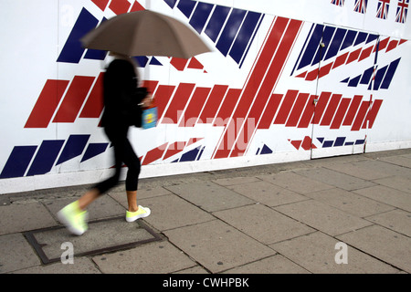 Femme avec un parapluie en passant un grand drapeau de l'Union dans le centre de Londres Banque D'Images