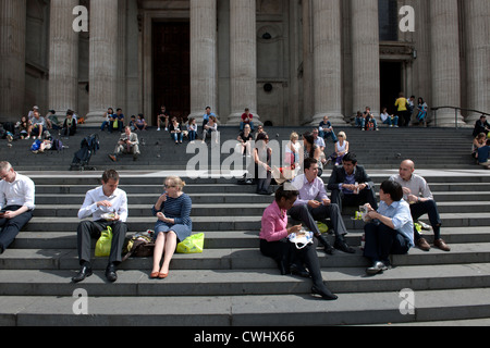 Les employés de bureau en train de déjeuner sur les marches de St Paul's à Londres, Angleterre Banque D'Images