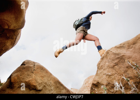 Black woman jumping à travers les rochers Banque D'Images