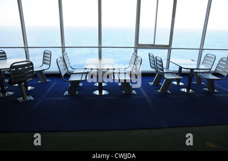 Tables et chaises en acier vide, fixé sur le pont, la fenêtre du sol au plafond, vue sur la mer, sol bleu foncé, cruise ferry, Golfe de Gascogne. Banque D'Images