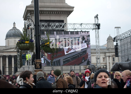 Les membres de la société Red Hat sur un bus panoramique ouvert sur l'écran d'affichage à Trafalgar Square, montrant le nouvel ans Day Parade Banque D'Images