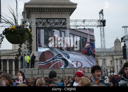 Les membres de la société Red Hat sur un bus panoramique ouvert sur l'écran d'affichage à Trafalgar Square, montrant le nouvel ans Day Parade Banque D'Images