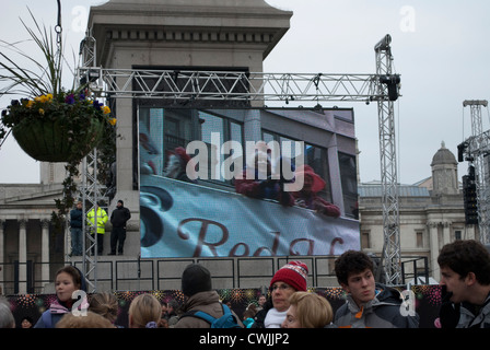 Les membres de la société Red Hat sur un bus panoramique ouvert sur l'écran d'affichage à Trafalgar Square, montrant le nouvel ans Day Parade Banque D'Images