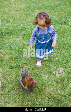 Petite fille chassant un poulet sur une visite d'une ferme de la ville, Banque D'Images