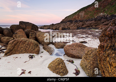 Lever du soleil à Porthgwarra à Cornwall avec des algues sur la plage à marée basse. Banque D'Images