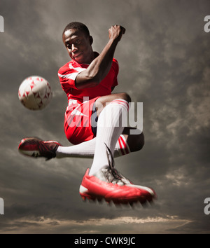 Soccer player kicking ball noir Banque D'Images