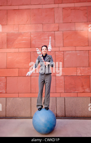 Caucasian businesswoman standing on ball juggling Banque D'Images