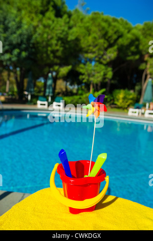 Jouet en plastique avec godet et moulin à vent proche piscine Banque D'Images