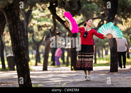 Une vieille femme chinoise tai chi pratiques arts martiaux danse du ventilateur de l'exercice tôt le matin au Temple du Ciel Park Banque D'Images