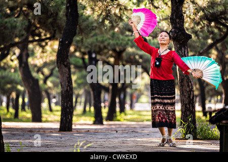 Une vieille femme chinoise tai chi pratiques arts martiaux danse du ventilateur de l'exercice tôt le matin au Temple du Ciel Park Banque D'Images