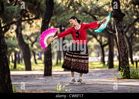 Une vieille femme chinoise tai chi pratiques arts martiaux danse du ventilateur de l'exercice tôt le matin au Temple du Ciel Park Banque D'Images