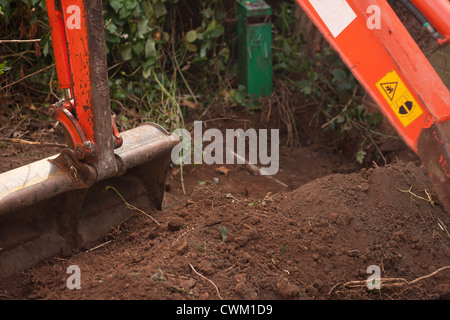 Un petit digger faisant un trou dans le sol Banque D'Images