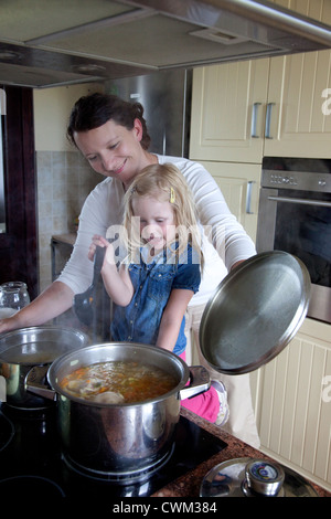 Aider maman polonaise fille age 4 cook à cuisinière faire de la soupe. Zawady Centre de la Pologne Banque D'Images