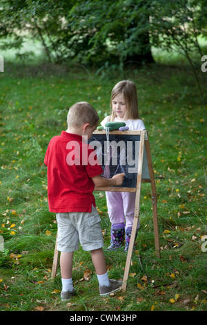 Jeune garçon et fille dessin sur tableau dans l'air extérieur champ age 6 et 8. Zawady Centre de la Pologne Banque D'Images