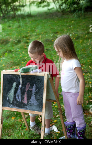 Jeune garçon et fille dessin sur tableau dans l'air extérieur champ age 6 et 8. Zawady Centre de la Pologne Banque D'Images