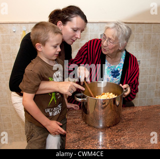 Maman et grand-mère polonaise soulignant le sort des tranches de pomme au jeune fils de 6 ans Zawady Centre de la Pologne Banque D'Images