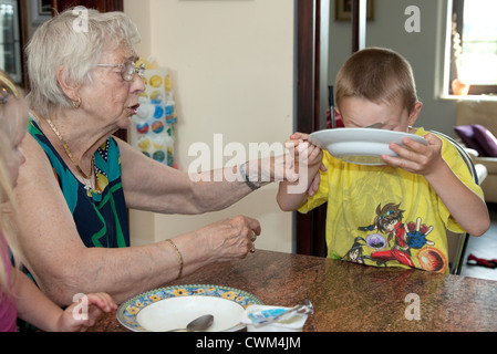 Grand-mère polonaise aidant petit-fils terminer sa soupe age 86 et 6. Zawady Centre de la Pologne Banque D'Images