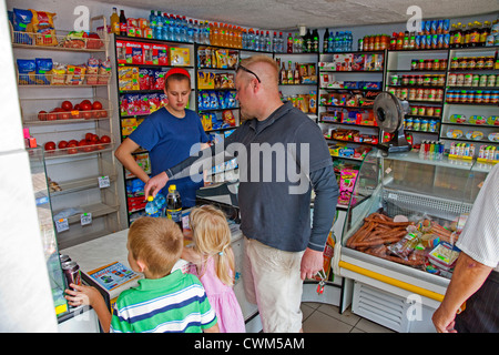 L'achat d'eau, de cola et de collations dans une petite épicerie commodité polonais sklep. La Pologne centrale Krolowa Wola Banque D'Images