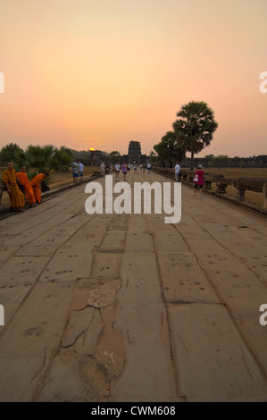 Vue verticale de moines assis le long de la chaussée de Naga à Angkor Wat à Siem Reap au coucher du soleil. Banque D'Images