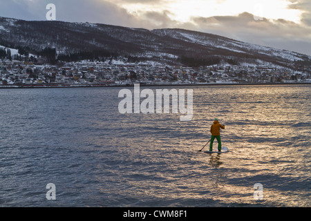 La Norvège, Narvik, Mature man paddling dans l'océan polaire Banque D'Images
