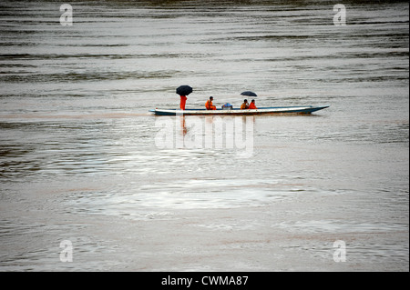 Quatre moines bouddhistes de parapluies dans un canot sur la rivière Nam Khan à Luang Prabang, Laos. Banque D'Images