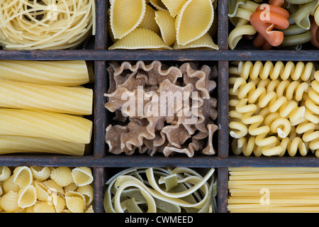 Différents types de pâtes alimentaires sèches dans un plateau en bois Banque D'Images