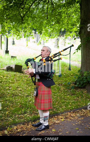 Un homme en kilt écossais traditionnel et joue de la cornemuse robe d'annoncer l'arrivée de la mariée Banque D'Images