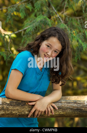 Young Girl leaning on log avec arbres en arrière-plan Banque D'Images