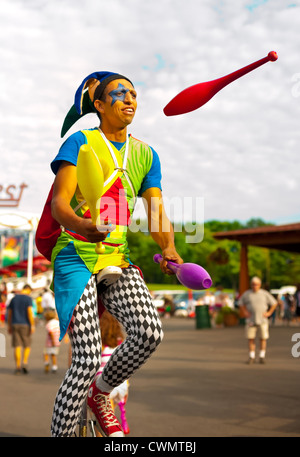 25 août 2012 - Middlebury, Vermont, États-Unis - jongleur en costume d'Arlequin sur les broches de jonglerie monocycle à Quassy Amusement Park. Banque D'Images