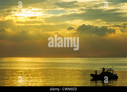 Groupe d'hommes de la marine à patrouiller la baie de Manille, Philippines, au coucher du soleil Banque D'Images